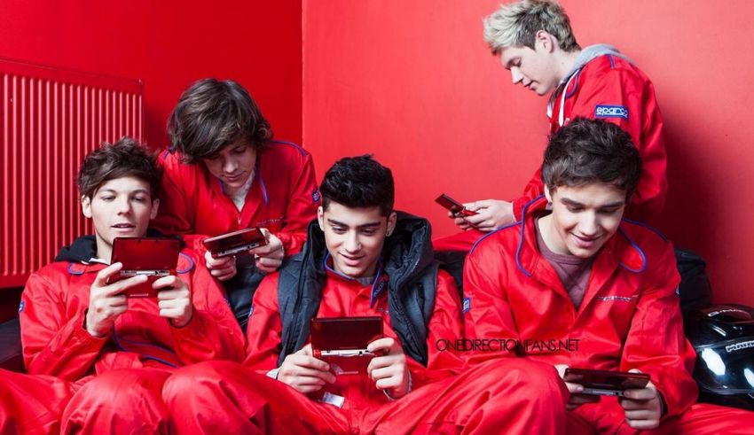 A group of young men in red jumpsuits looking at their cell phones.