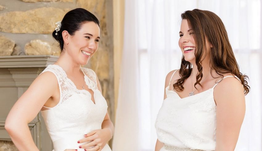 Two brides laughing in front of a fireplace.
