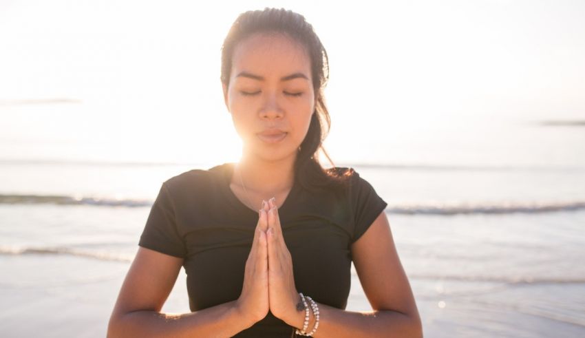 A young woman meditating on the beach.