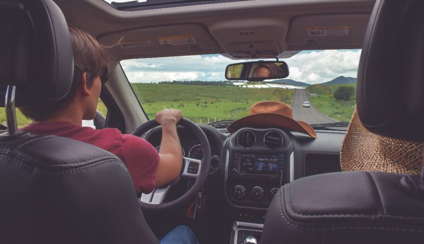 A man and woman driving a car in the countryside.