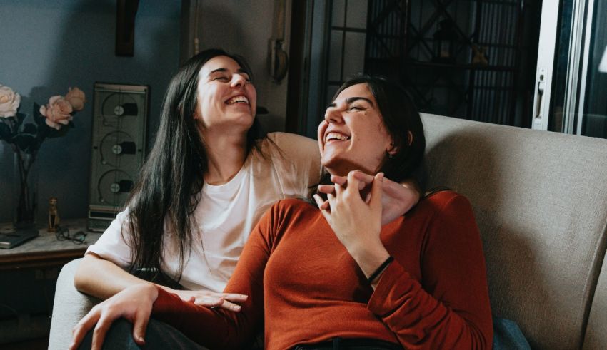 Two women laughing on a couch.