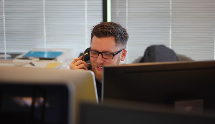 A man talking on the phone in front of a computer.