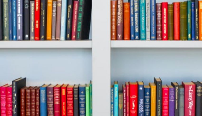 A row of colorful books on a white shelf.