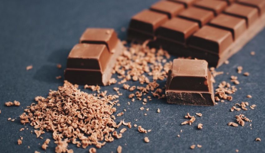 A piece of chocolate is sitting on top of a piece of granulated sugar.