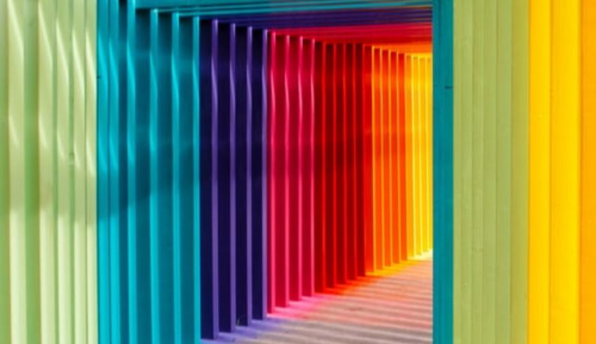 A rainbow colored hallway leading to a building.