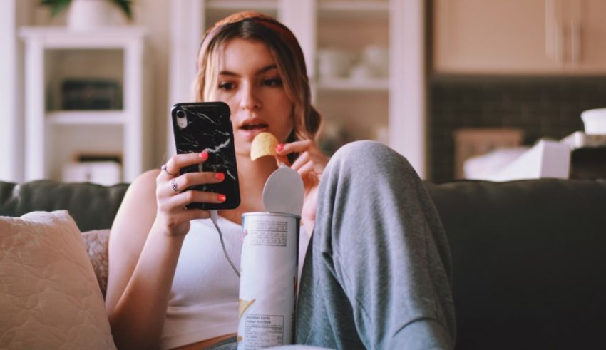 A woman sitting on a couch with a cell phone in her hand.