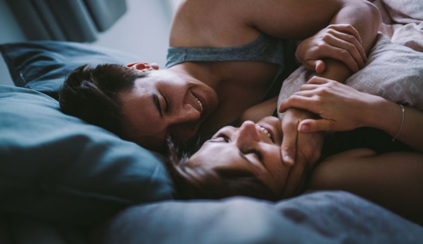 A man and woman are laying in bed together.