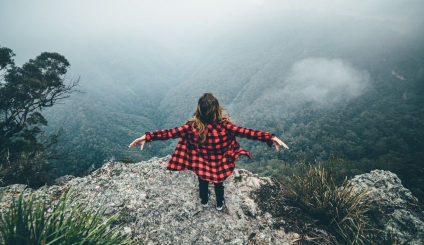 A woman standing on top of a mountain with her arms outstretched.