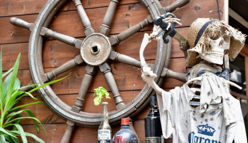 A skeleton sits on a wooden table next to a bottle of wine.