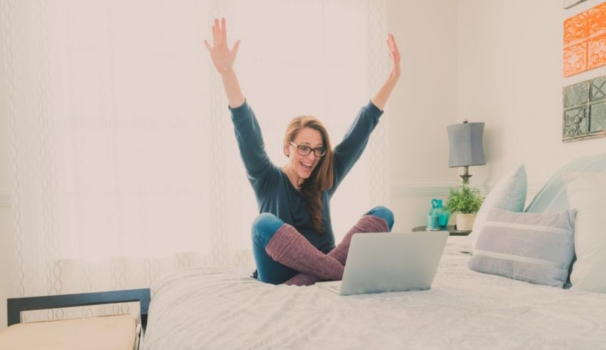 A woman is sitting on a bed with her arms raised.