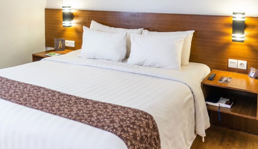 A hotel room with a white bed and wooden headboard.