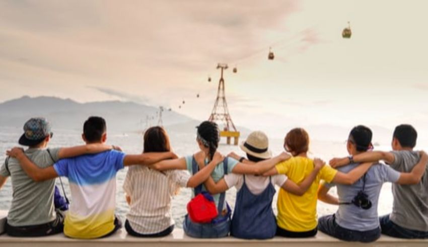 A group of people sitting on a ledge looking at the ocean.