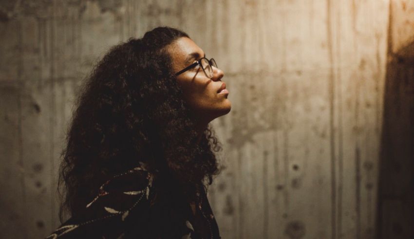 A woman in glasses standing in front of a wooden wall.