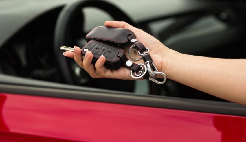 A person holding a key to a red car.