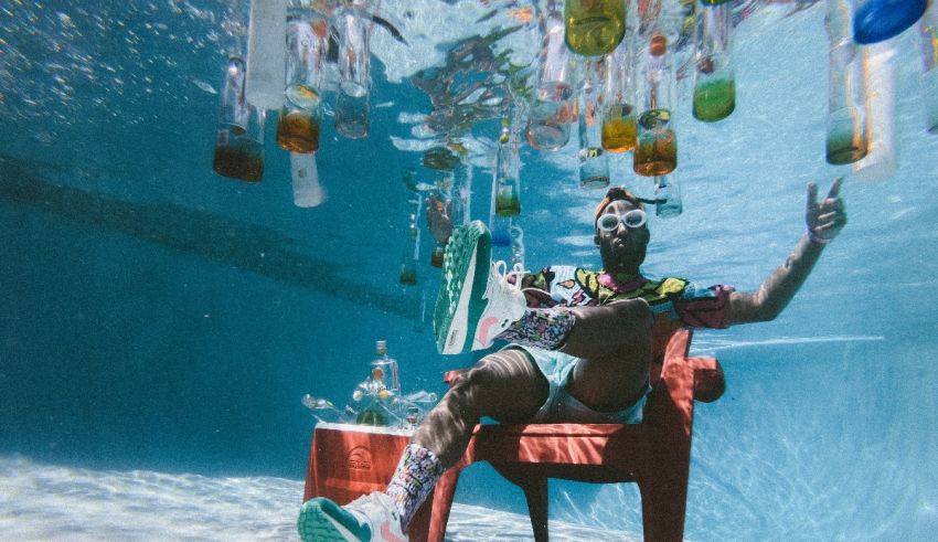 A man sitting in a chair under the water with bottles.