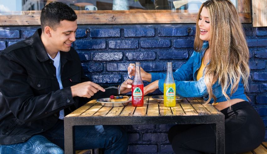 A man and woman sitting at a table eating food.