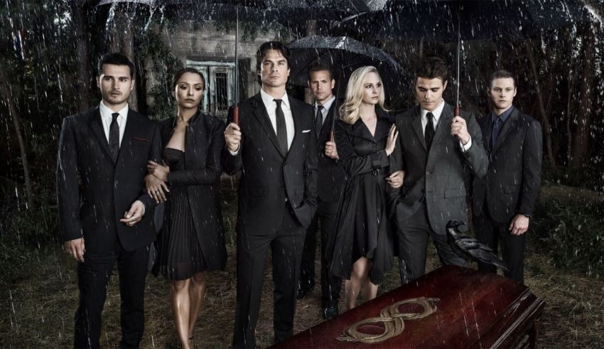 The vampire diaries cast standing in front of a casket.