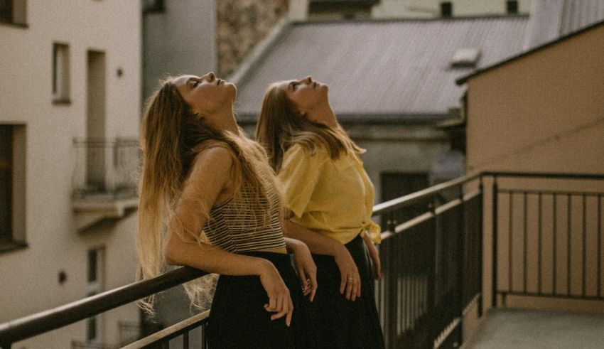 Two women standing on a balcony looking up at the sky.