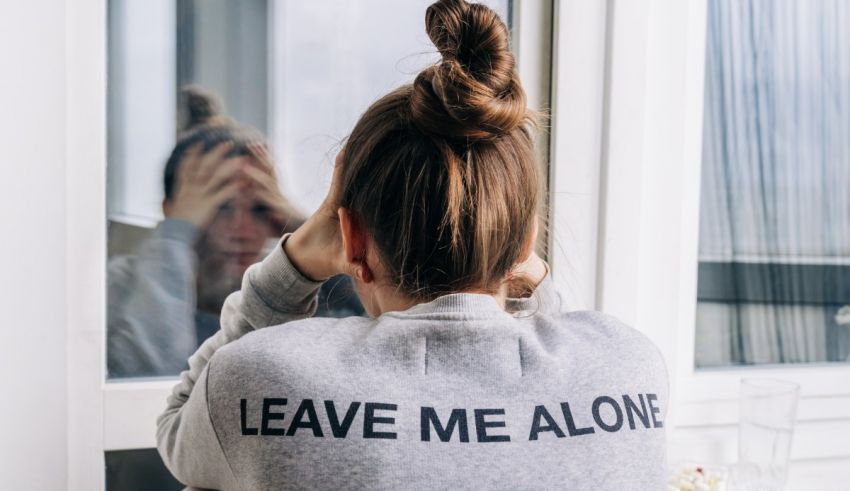 A woman looking at herself in the mirror with the words leave me alone.