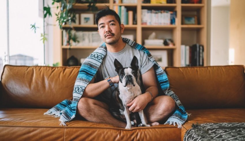 A man sitting on a couch with his dog.