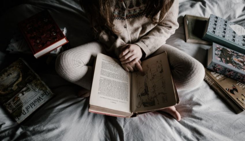 A girl reading a book on a bed.