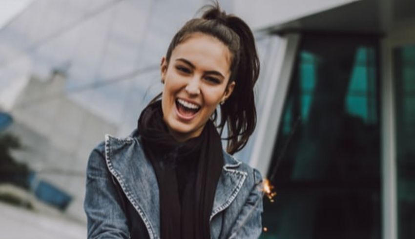 A young woman is laughing while holding a cell phone.