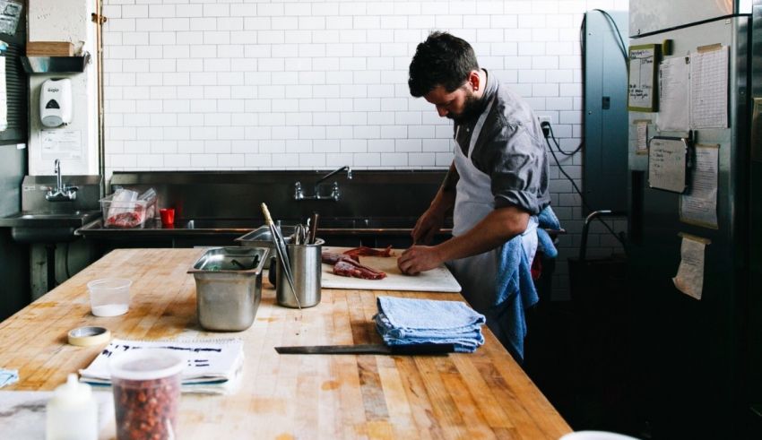 A man in an apron is preparing food in a kitchen.