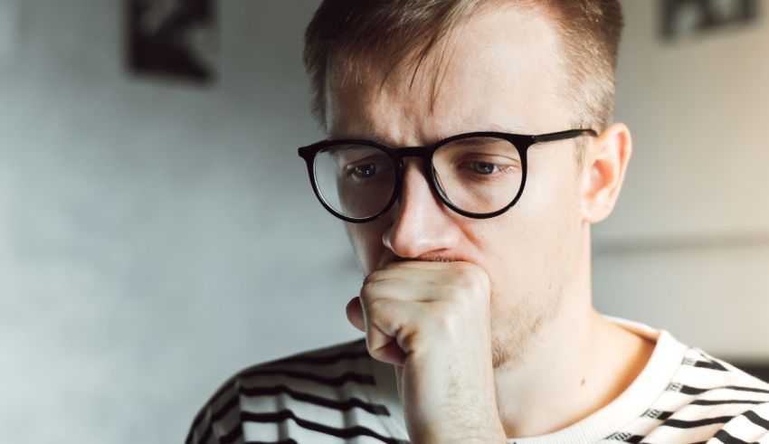 A man in glasses with his hand on his chin.