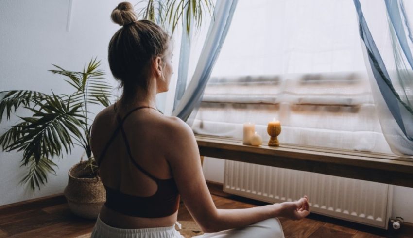 A woman meditating in front of a window.