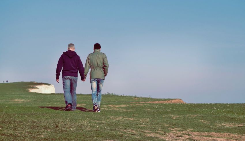 Two people walking on a grassy hill.
