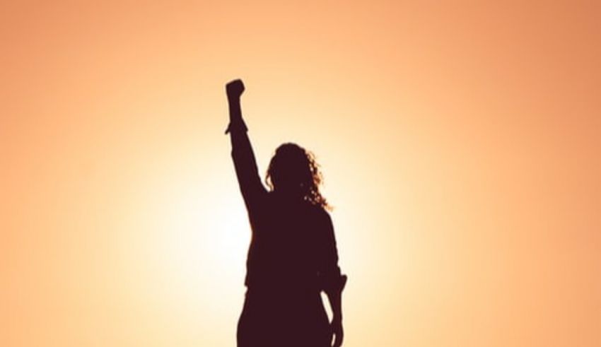 A silhouette of a woman raising her fist in the air.