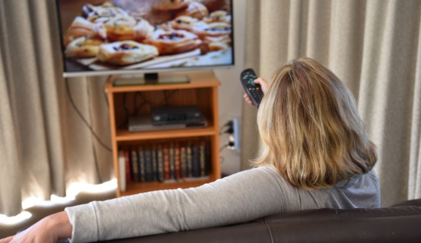 A woman holding a remote control in front of a tv.