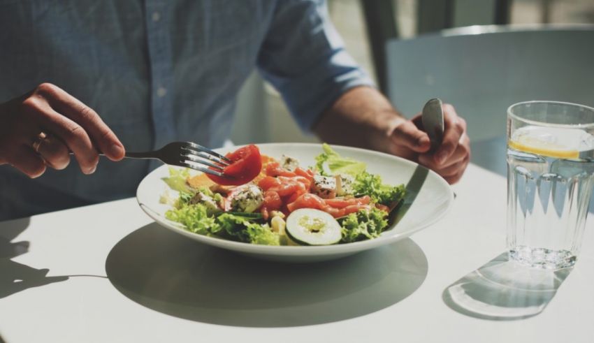 A man is eating a salad with a fork.