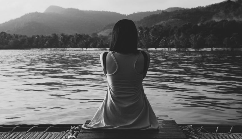 A woman sitting on a dock looking at the water.