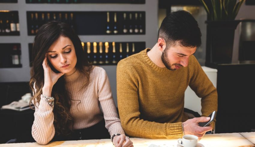 A man and woman sitting at a table looking at their phones.