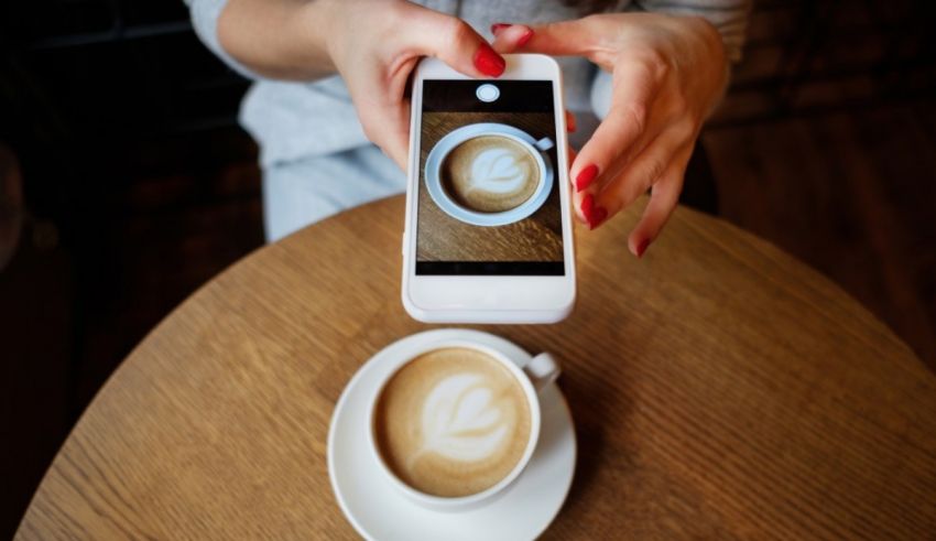 A person taking a picture of a cup of coffee.