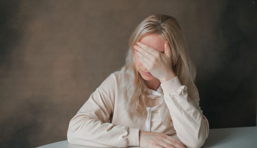 A blond woman covering her face with her hands.