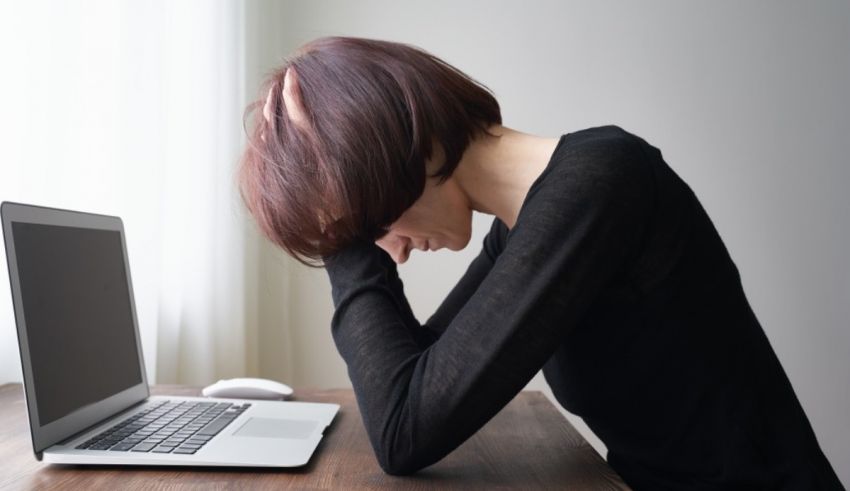 A woman is sitting at a desk with a laptop in front of her.