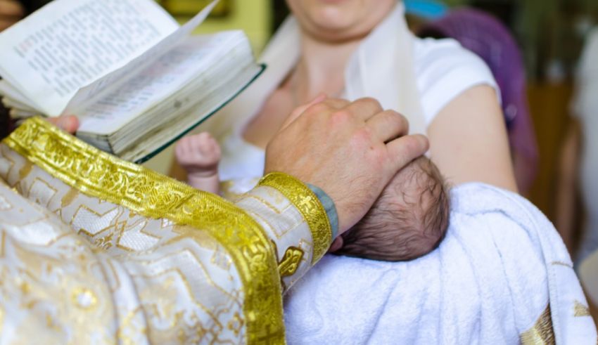 A baby is being baptized by a christian priest.