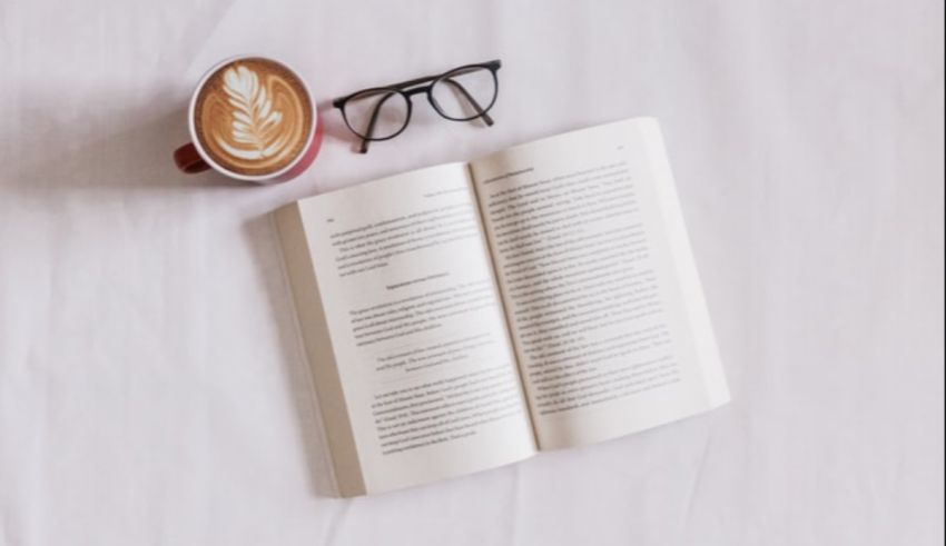 A book and glasses on a white surface.
