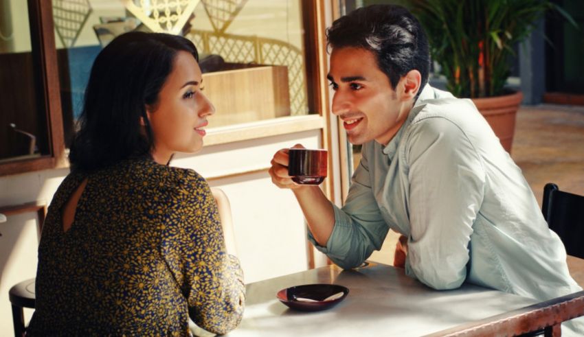 A man and woman are sitting at a table and drinking coffee.