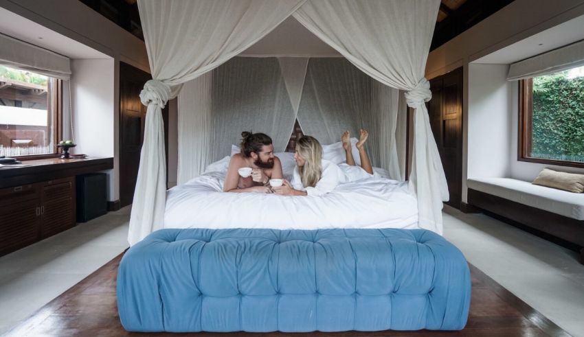 Two women sitting on a bed in a room with a canopy.