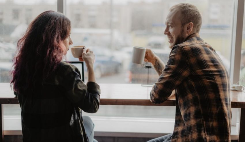 A man and woman sitting at a table with coffee cups.