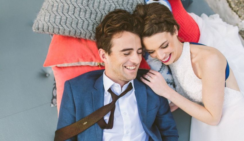 A bride and groom laying on a bed.