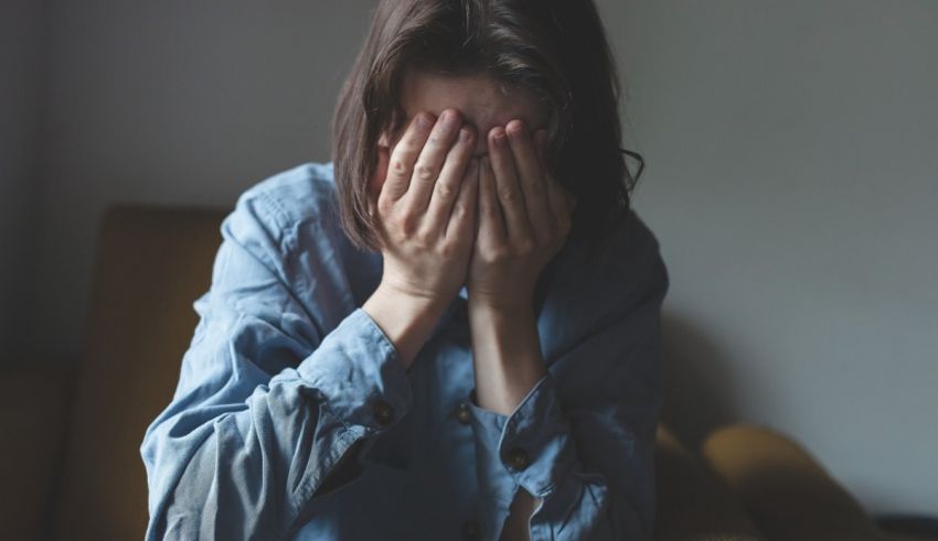 A woman covering her face with her hands.