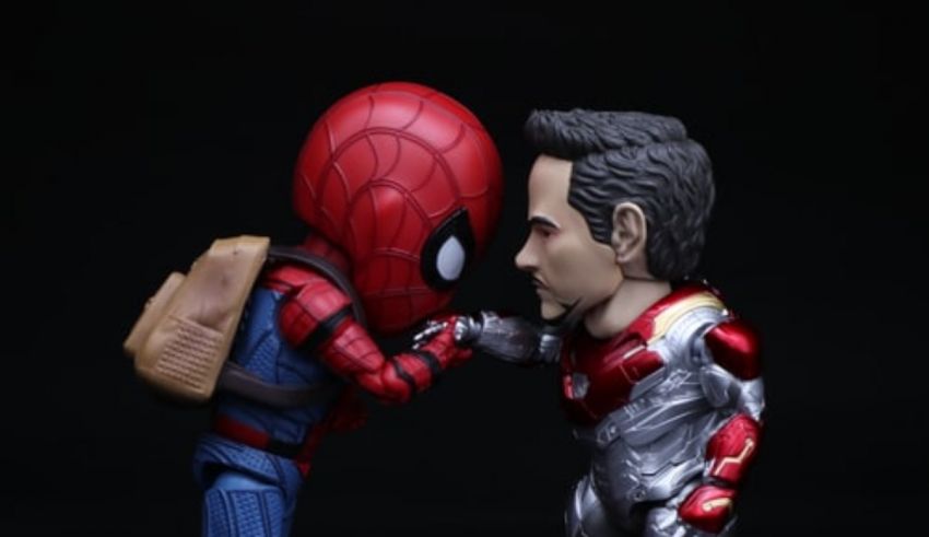 A spider - man and iron man figure are touching each other.