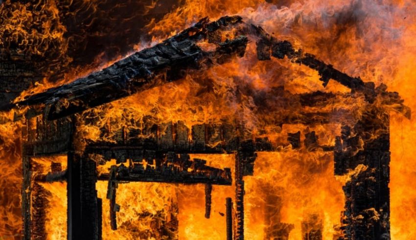 A house on fire with flames coming out of it.