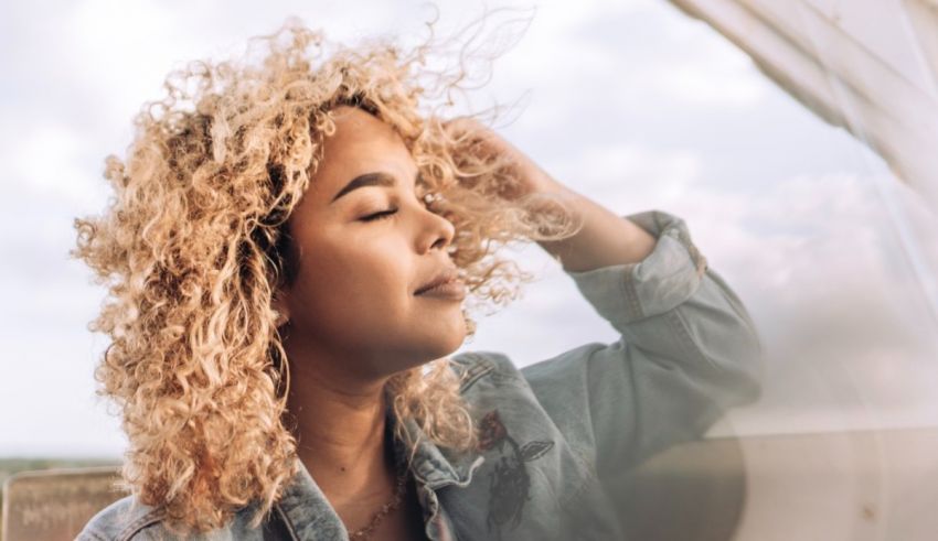A woman with curly hair looking out of a window.