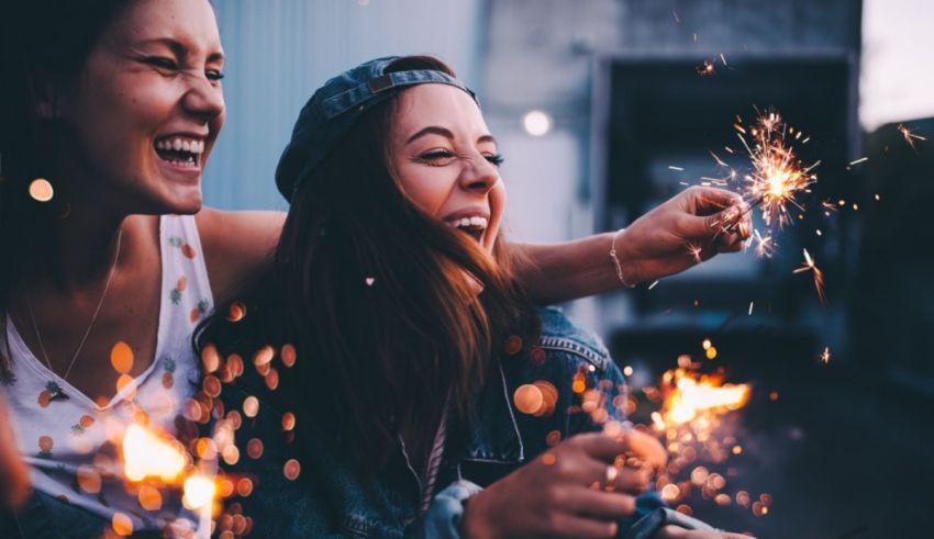 Two women laughing while holding sparklers.