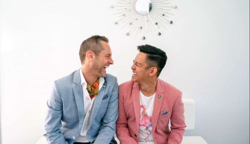 Two men laughing and sitting on a table.